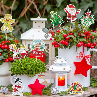 Tiny Royalty 12 Pcs Christmas Rhinestones Painting Kits displayed among festive greenery and decorations.