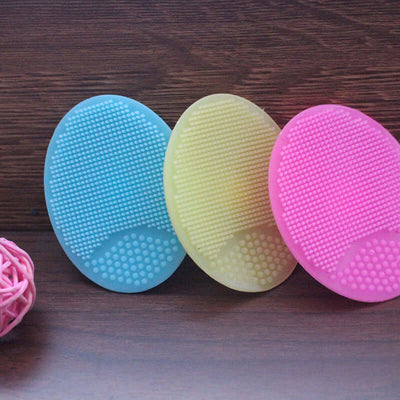 Tiny Royalty Baby Silicone Shampoo Bath Brush in blue, yellow, and pink colors on wooden background.