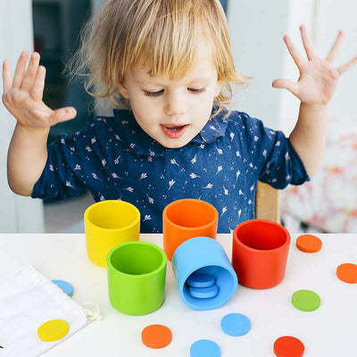 Tiny Royalty baby learning with colorful sorting cups and counting tokens during playtime.